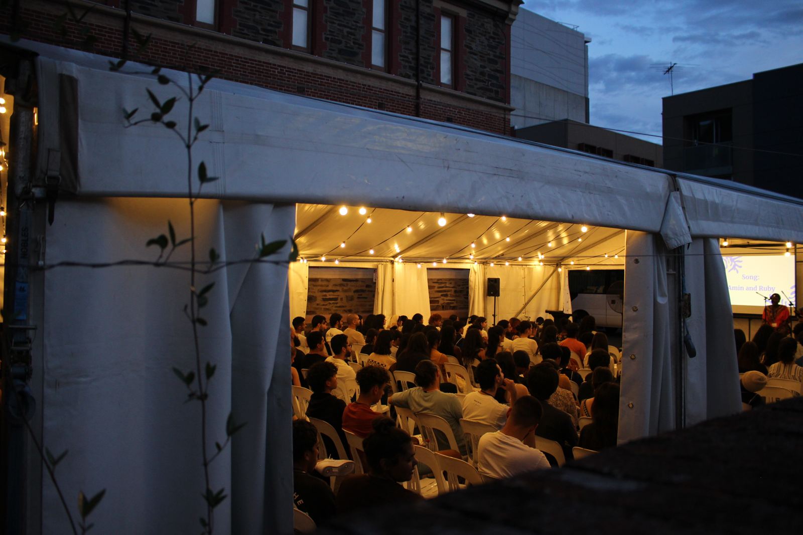 The conference marquee glowing with fairy lights at dusk, packed with young people